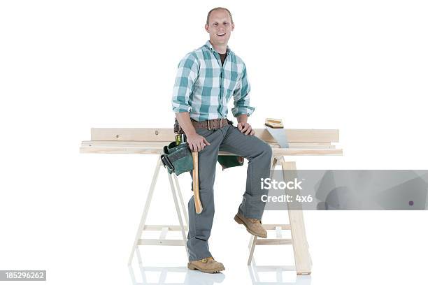 Carpenter Sittiing On A Sawhorse Stock Photo - Download Image Now - Sitting, Front View, Repairperson - Occupation