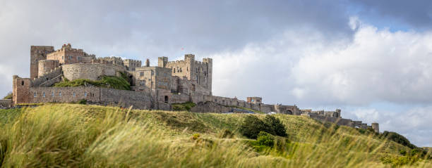 영국 노섬벌랜드주 뱀버그(bamburgh)의 모래 언덕에서 솟아오르는 뱀버그 성(bamburgh castle)의 해안 전망 파노라마 - bamburgh england castle fort 뉴스 사진 이미지
