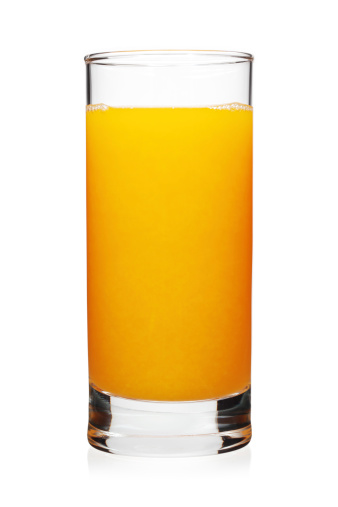Orange juice in glass with oranges outdoors on wooden table with nature background