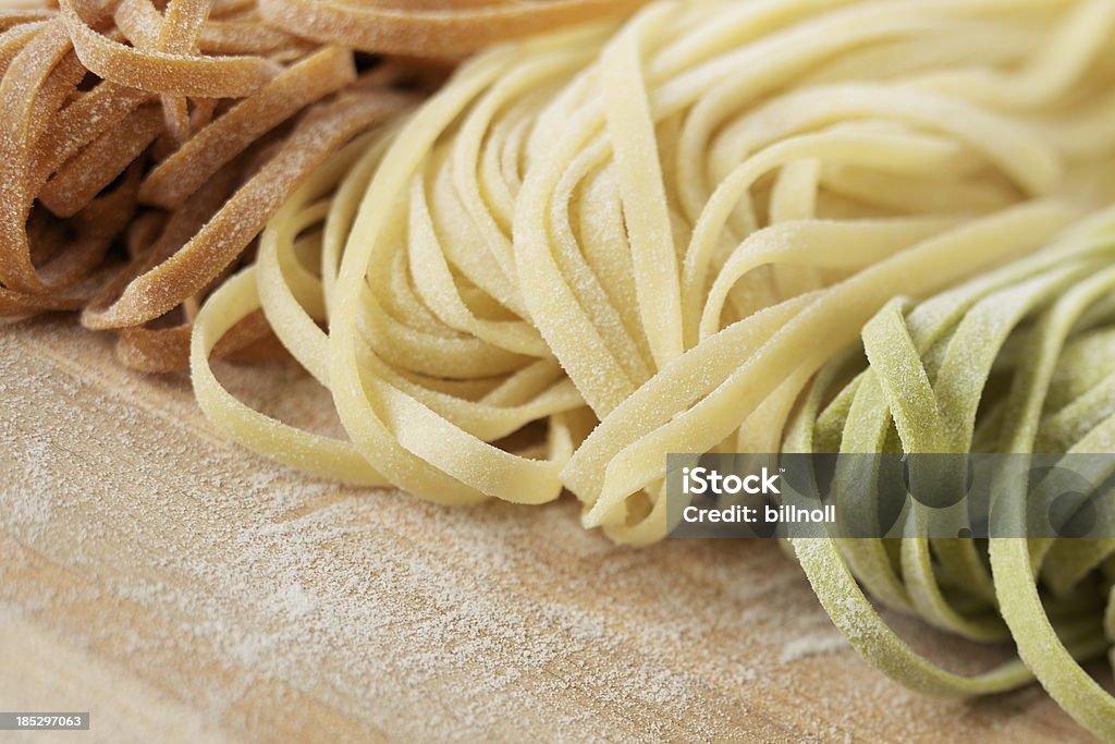 Fresh uncooked linguine pasta on wood Natural light image of fresh tri color linguine pasta on wood. The three colors represent the colors in the Italian flag. The red pasta is made with red peppers and the green pasta with spinachPlease view more modern food images here: Freshness Stock Photo