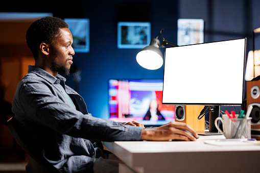 Freelancer looking at white blank screen on pc at home, working remotely with empty chromakey template. Young developer checking at isolated copyspace display layout at workstation.