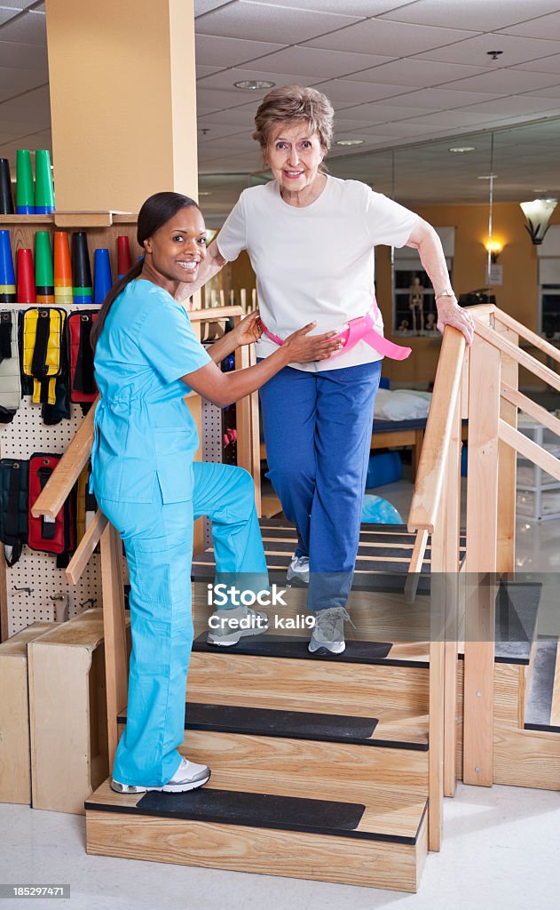 物理療法士のクライミングステアズ老人女性 - 内階段のロイヤリティフリーストックフォト