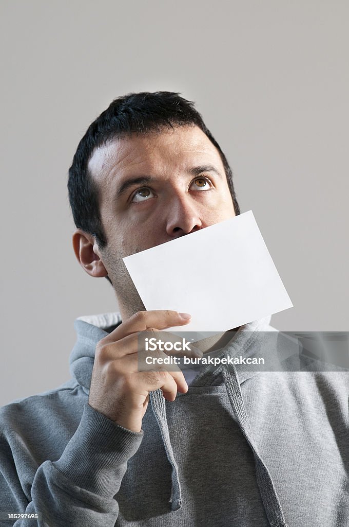 Hombre sosteniendo una tarjeta en blanco en frente de la cara - Foto de stock de Cara humana libre de derechos