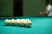 A group of friends plays billiards. The man hits the ball with a cue and hammers the meat into the pocket. People have fun playing billiards in the evening. Concept of a company playing billiards.