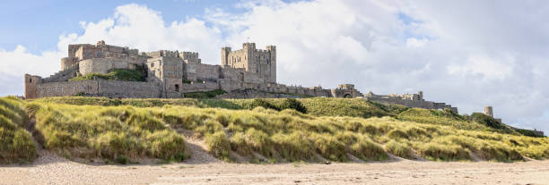 뱀버그(bamburgh)의 모래 언덕에서 솟아오르는 뱀버그 성(bamburgh castle)의 탁 트인 해안 전망, 노섬벌랜드, 영국 - bamburgh bamburgh castle sand dune history 뉴스 사진 이미지