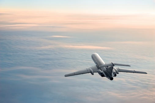 Passenger aircraft on the clouds background. Daybreak flight in stratosphere. Pastel colored image.