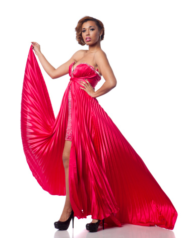 A beautiful mixed race woman in an elegant red gown photographed in the studio on a white background with a fashion pose.