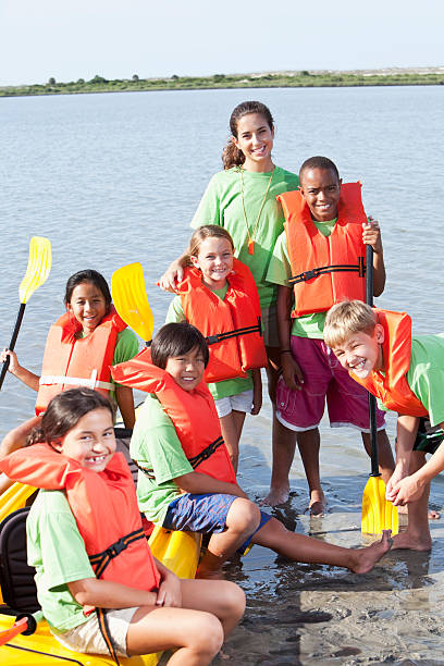 Summer camp counselor and children with kayak Teenage girl and group of children with kayak at water sports camp. kayaking photos stock pictures, royalty-free photos & images