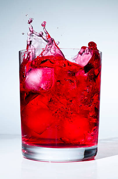 кубик льда плещущиеся на красная жидкость - drink alcohol juice red стоковые фото и изображения