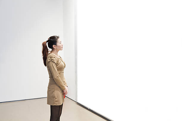 One woman looking at white frame in an art gallery stock photo