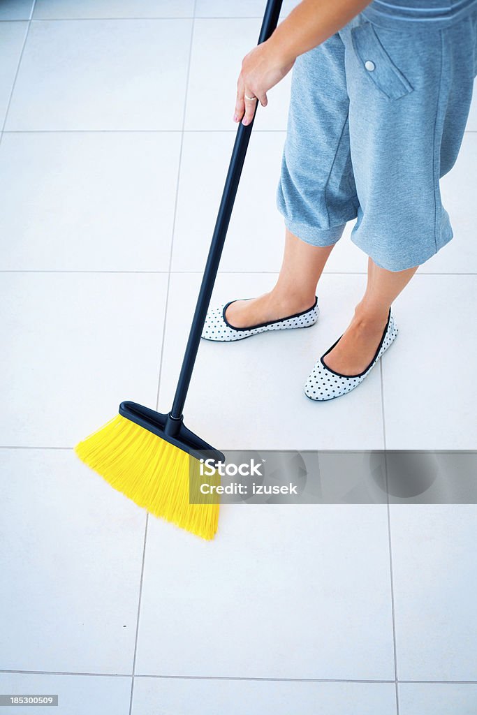 Cleaning floor Woman sweeping tiled floor using broom. Adult Stock Photo