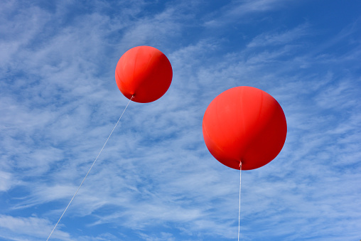 Red balloons. A giant inflatable red advertising balloon floats in the sunny blue sky.