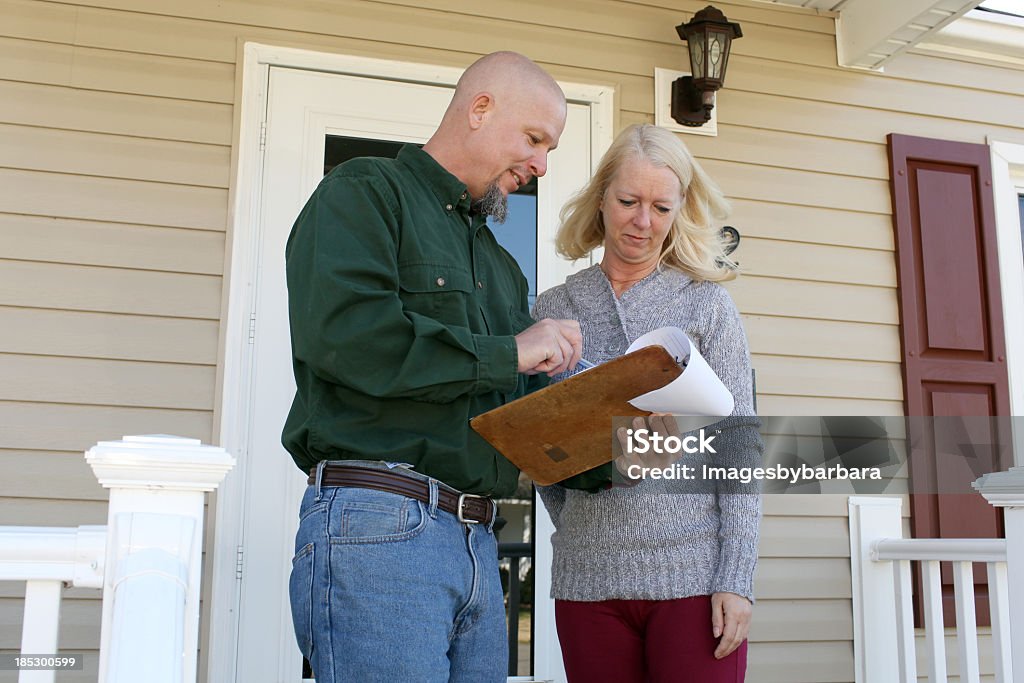 A woman talking to a home inspector on her front porch Contractor going over details of home inspection. Examining Stock Photo