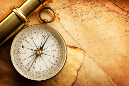A compass and a spyglass on an old textured map.