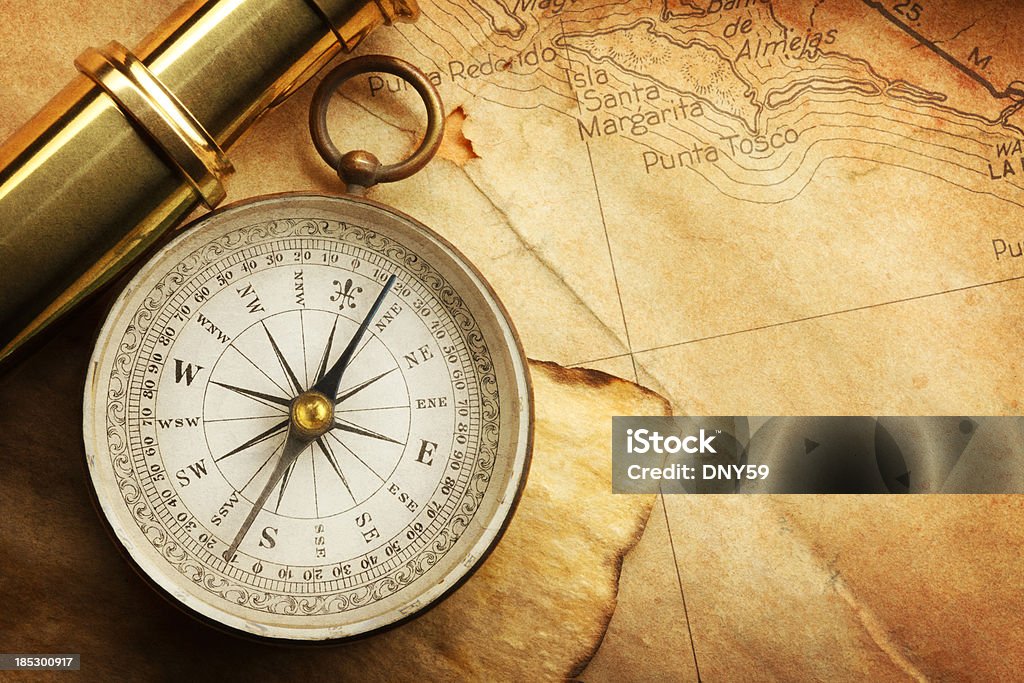Compass And Spyglass On A Map A compass and a spyglass on an old textured map. Navigational Compass Stock Photo