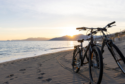 Bicycles on empty beach at sunset and distant hills