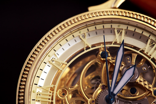 Golden wristwatch with a visible clockwork on black background