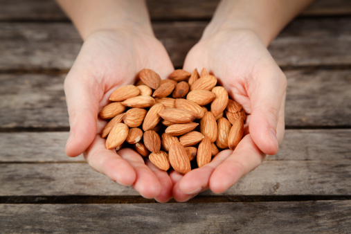 Young woman holding handful of fresh almond. SEE SIMILAR IMAGES