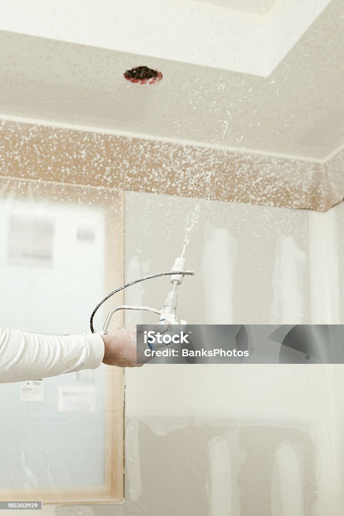 Trabajador pulverización de yeso Mud en un techo para Knockdown textura - Foto de stock de Placa de yeso libre de derechos