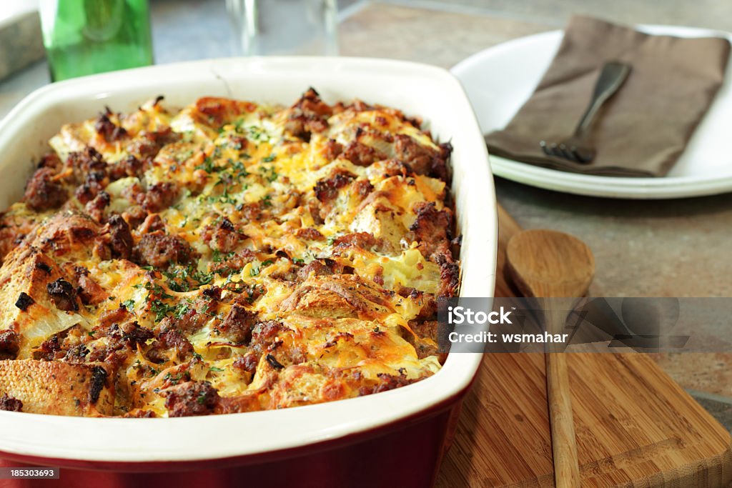 Savory breakfast casserole next to wooden spoon A bread pudding casserole made from French baguette bread, sage breakfast sausage, onions and cheddar cheese Casserole Stock Photo