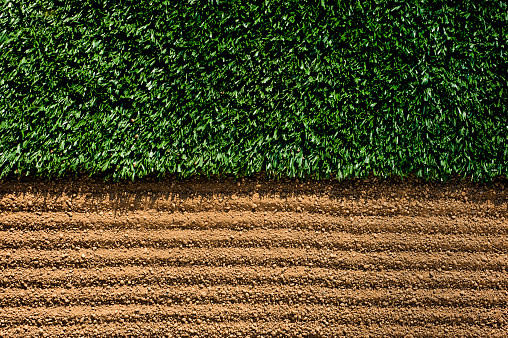 Manicured Sports Field. Freshly manicured dirt with rake grooves next to artificial turf as the sun casts shadows.