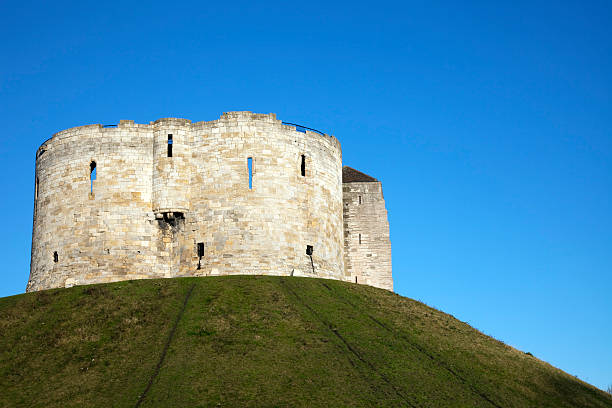 York Castle, Clifford's Tower "York Castle dates from 1068 following the Norman invasion of York. Henry III rebuilt the castle in stone in the middle of the 13th century, creating a keep with a unique quatrefoil design, and this keep became known as Clifford's Tower, and is a well-known tourist destination. Built high on a mound, this motte-and-bailey castle has commanding views over the city." bailey castle photos stock pictures, royalty-free photos & images