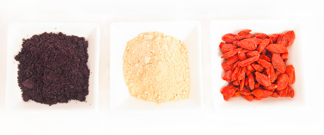 Superfood collection - Goji berries, acai powder and maca root powder, popular functional food, in small white dishes, studio shot, white background.