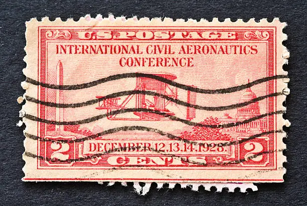 "The 2-cent red stamp for the International Civil Aeronautics Conference, issued on December 12, 1928, shows the Wright Brothers' airplane in flight, flanked by the Washington Monument on the left and the U. S. Capitol on the right. The conference coincided with the 25th anniversary of the Wright Brothers' first powered flight."