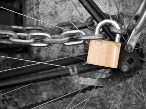 Gold bicycle lock on a black and white image of a bicycle.