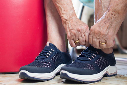unrecognizable elderly woman tying her shoelaces for exercise and walking.vitality and sport in old age and healthy lifestyle.