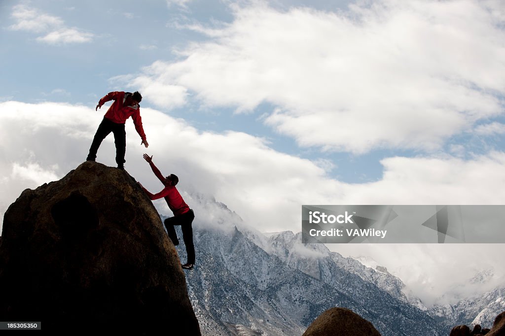 Mann oben auf dem Berg dass jemand bis - Lizenzfrei Bergsteigen Stock-Foto