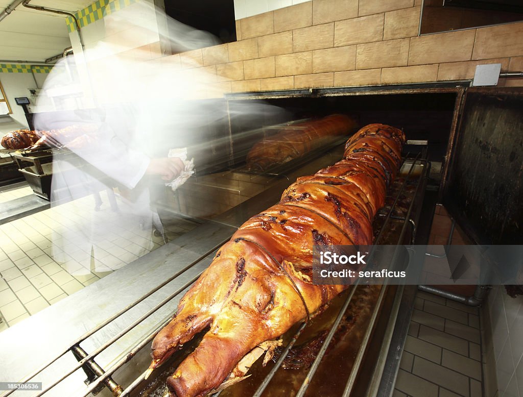 Roasting porchetta "A cook, shot with blurred motion, preparing porchetta, an italian speciality, in a food processing plant. Porchetta it is made enclosing pork meat with spices and herbs in the animal's skin and roasting it whole.Other images in:" Adult Stock Photo