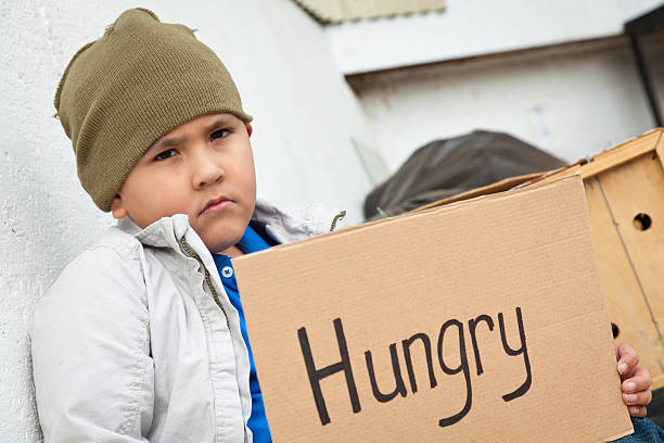 istock young boy holding a cardboard hungry sign 185307030