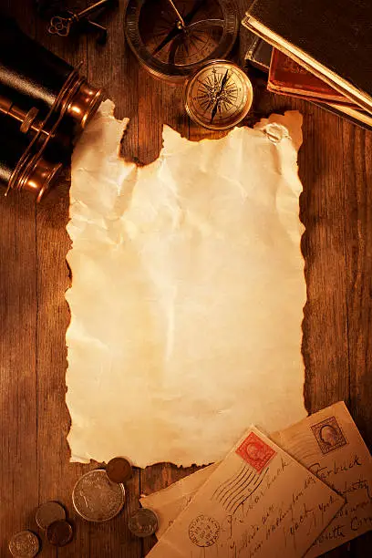 "This is an overhead photo of a blank sheet of parchment paper surrounded by letters,coins, binoculars, compass and books. There is a lot of space for copy.Click on the links below to view lightboxes."