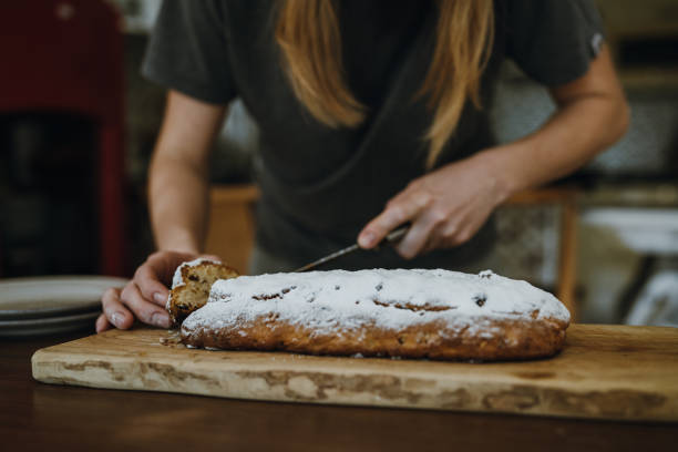 istock Women's hands cutting fruitcake with knife. 1853083503