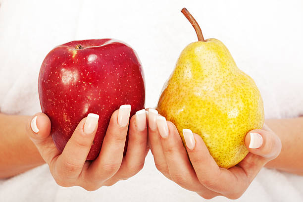 Young woman holding apple and pear in her hands, isolated on white