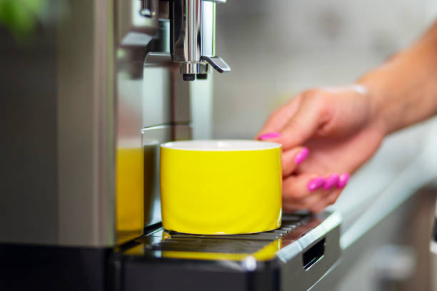 A young woman makes fresh flavored coffee with a modern coffee machine in her kitchen.