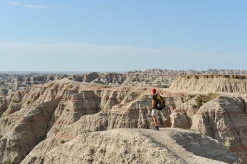 Man hiking with backpack on top of Badlands.