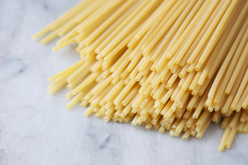 Natural light photo of dried bucatini also called pasta tubes on light colored marble counterPlease view more modern food images here: