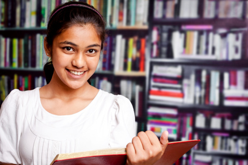 Indian Teenager Girl studying in a Library with Bookshelf