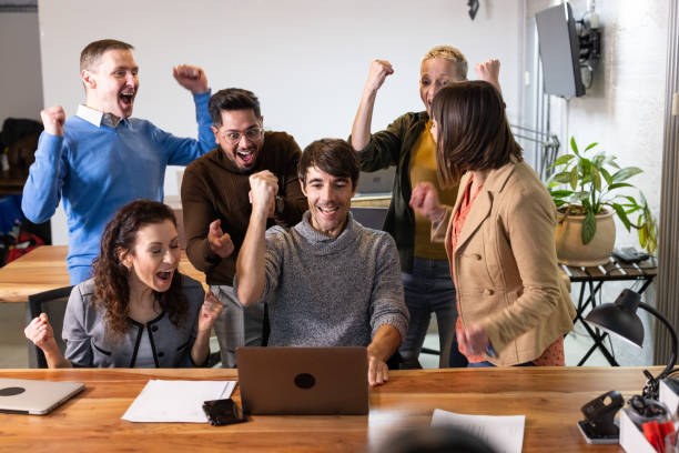 istock Group of diverse businesspeople cheering while looking at a laptop at work 1853100296