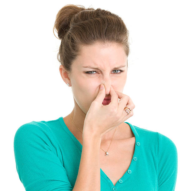 Young Woman Pinching Nose Portrait of a young woman on a white background. http://s3.amazonaws.com/drbimages/m/ap.jpg holding nose stock pictures, royalty-free photos & images