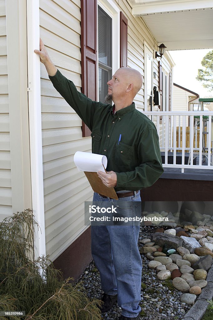 Home Inspection Adult male contractor inspecting the down spout of a home that is being bought. 20-24 Years Stock Photo