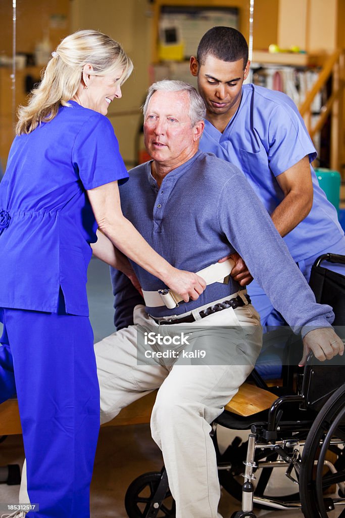 Fisioterapisti aiutando il paziente in sedia a rotelle - Foto stock royalty-free di Paziente