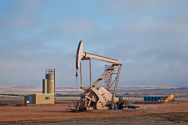 "Oil pumper with natural gas burn-off flame in background. Brakken Oil Fields, ND."