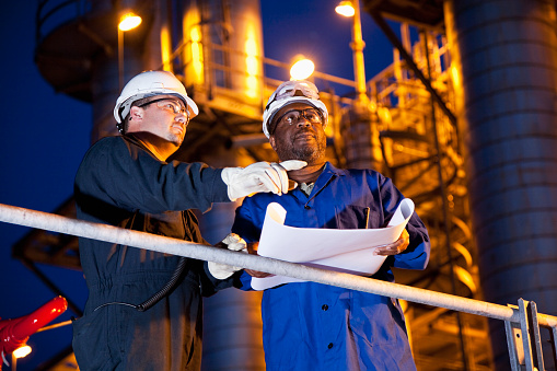 Multi-ethnic engineers working at chemical plant at night.