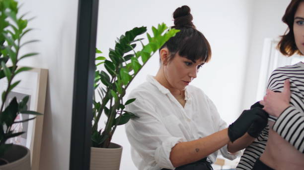 istock Focused tattooist working client studio closeup. Artist customer looking mirror 1853146895