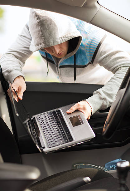 istock Hooded thief stealing a laptop from a car 185314830
