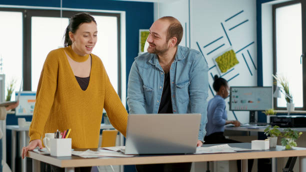istock Smiling coworkers in office looking at laptop screen comparing business analytics with sales charts 1853154217