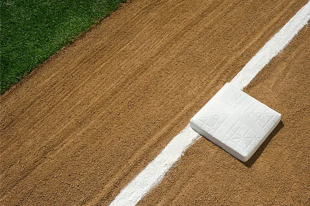 A baseball or softball third base with new white chalk baseline before the start of the game